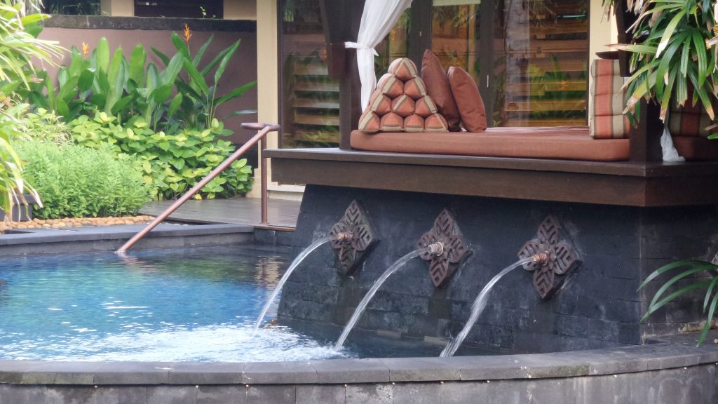 Wasser fließt aus einem Brunnen in einen Pool im St Regis Bali